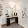 Furnished accessible bathroom with roll-under vanity and walk-in shower with grab bars