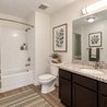 Bathroom with tub and shower combo, granite vanity, and dark wood cabinets