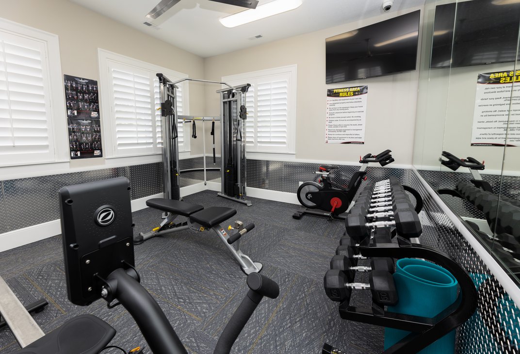 Resident fitness room with cable machine, bench, bike, and dumbbells